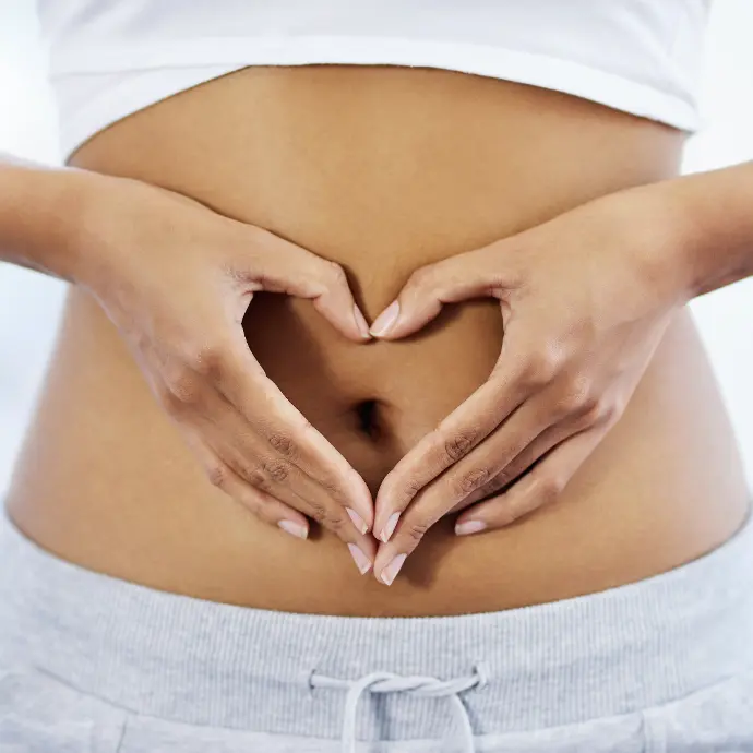A woman with her hands in a heart shape over her stomach