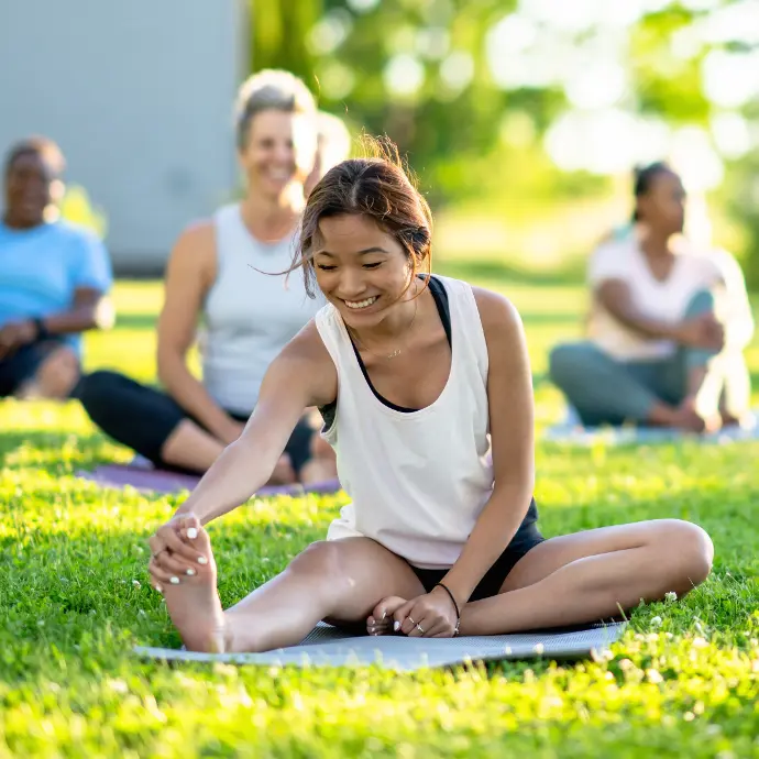 A smiling woman doing yoga on the grass