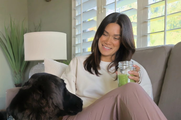 A beautiful woman drinking Ultimatcha and petting a cute dog